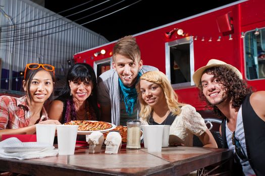 Group of five adults smiling at table near mobile cafe