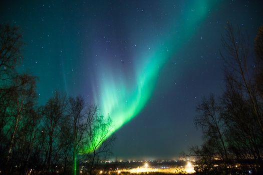 Northern lights and Big Dipper shine brightly over a city