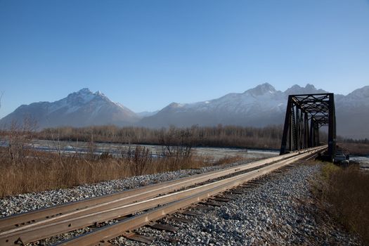 Narrow bridge spans river in Alaska.