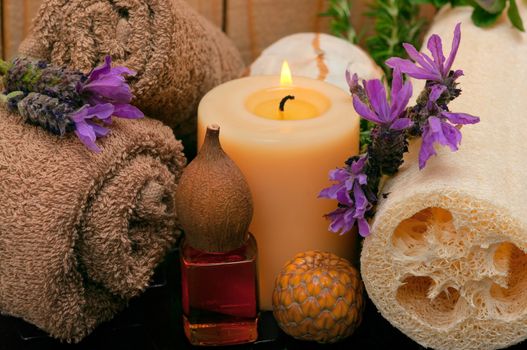 spa concept with cotton towels, massage oil, loofah, aromatic lavender and candles