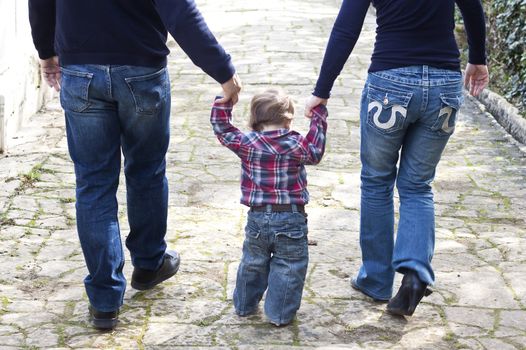 Mother and father walking with their baby child between them in a park