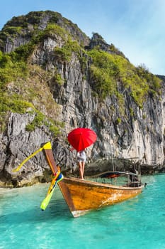 Girl with a red umbrella on a boat at a resort in Thailand