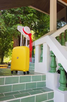 Orange travel case and sun hat on the stairs at the entrance to the hotel