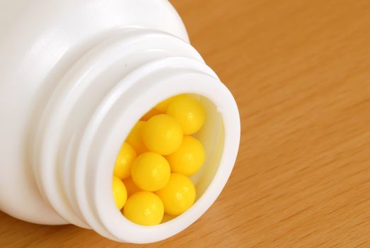 yellow vitamin pills and white plastic bottle pack closeup macro
