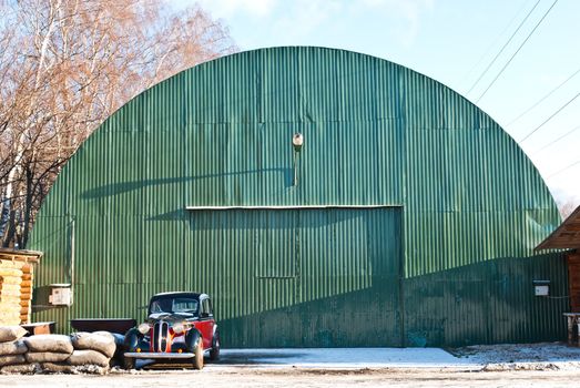 Old green aircraft hanger with classic car park in front, taken on a sunny winter morning
