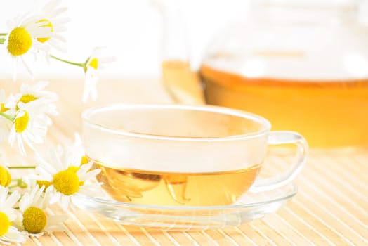 A teacup and a teapot with herbal chamomile tea