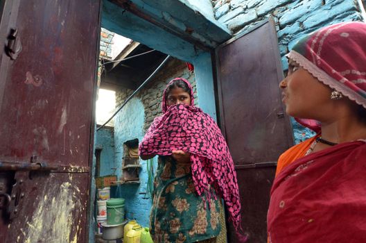 New Delhi,India-February 4, 2013: two  women speak in the courtyard of his house in the slum in New Delhi. In India dramatically increases the number of poor people living in slums
