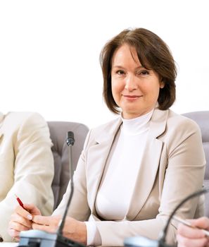 Portrait of a senior business woman at the meeting, sitting at a table on which are microphones