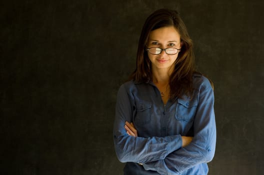 Confident woman with arms crossed against a blackboard background