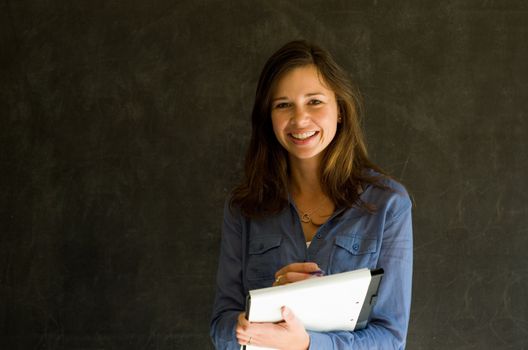 Confident woman with notepad and pen against a blackboard background