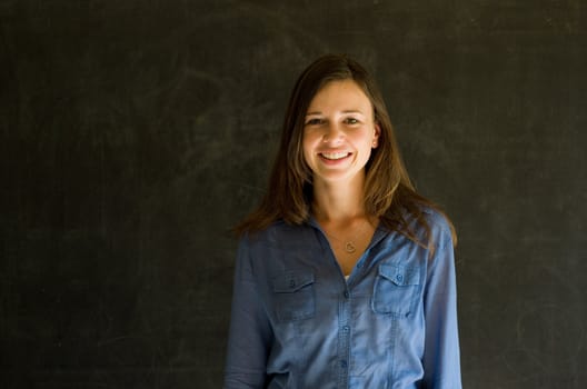 Confident woman with arms crossed against a blackboard background