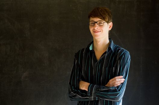 Confident man with arms crossed against a blackboard background