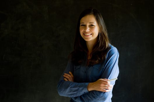 Confident woman with arms crossed against a blackboard background