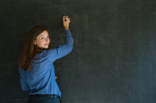 Confident woman teacher writing on blackboard background