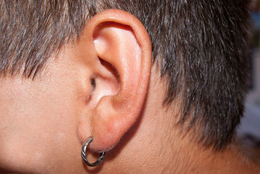 Ear of an adult male close-up with silver earring