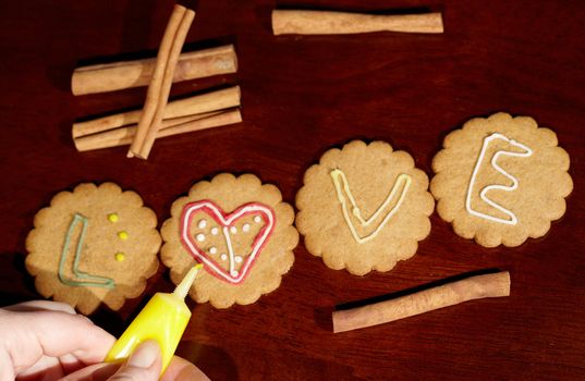 Drawing on ginger cookies. The word love.