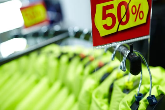 Clothes on hangers in the shop with fifty percent discount.