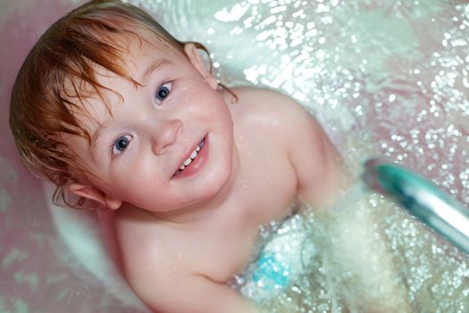 Closeup portrait of the little 2 year old boy taking a bath.