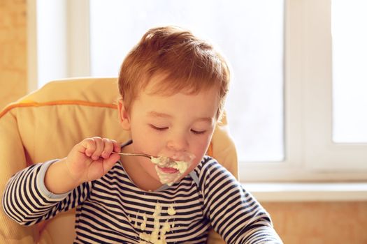 Portrait of two year old boy eating porridge in the morning.