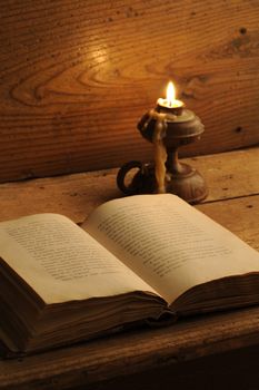 old book on a wooden table by candlelight