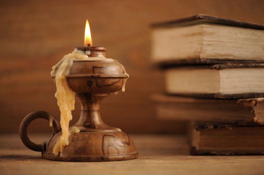 old candle on a wooden table, old books in the background