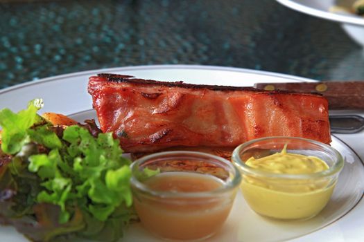 closeup of ham steak and green salas serve with mastard and honey sauce