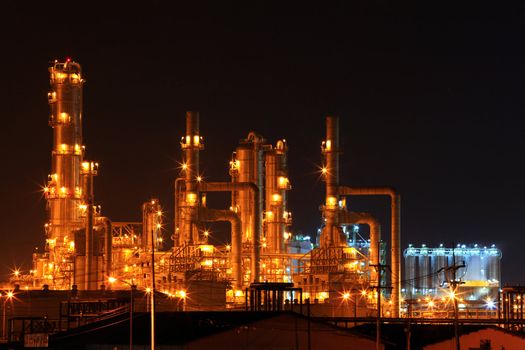 scenic of petrochemical oil refinery plant shines at night, closeup