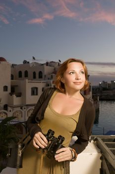 Tourist woman with binoculars in the evening at seaside