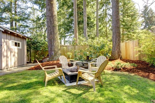 Home exterior Backyard with chairs and pine trees. Spring.