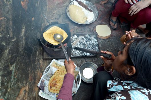 New Delhi,India-February 4, 2013:woman cooking chapatis in oil to make pancakes, in February 4,2013 in Dehli, India. Chapatis are the staple diet of all Indian people