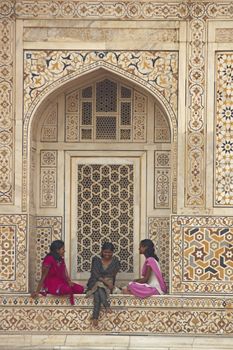 Indian teens in colorful sari's sitting in the alcove of a beautiful Mughal Tomb, I'timad-ud-Daulah in Agra, Uttar Pradesh, India