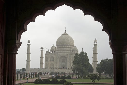 Taj Mahal. White marble tomb set on raised platform topped by large oval dome. Framed in Mughal arch. Agra, Uttar Pradesh. India