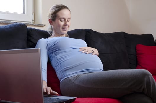 pregnant woman working from home smiling looking at her belly