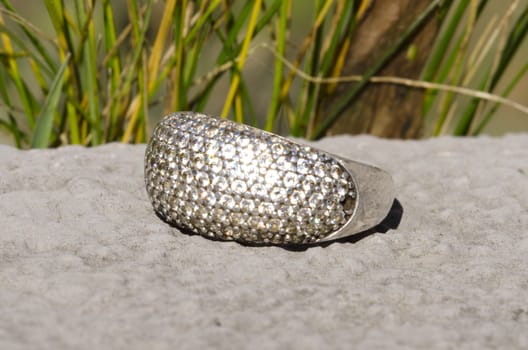 close up of silvery  ring outdoor shining in the sun with grass in the background