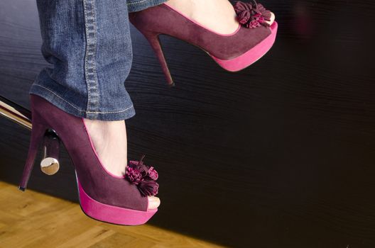 close up of a woman wearing purple shoes with high heels sitting on bar stool