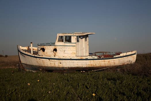 an old abandoned boat out of water with a blue sky.