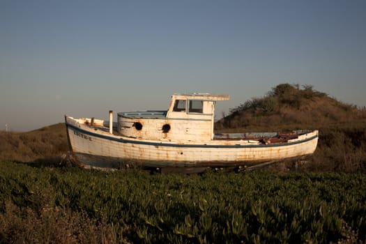 an old abandoned boat out of water with a blue sky.