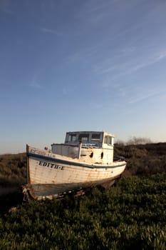 an old abandoned boat out of water with a blue sky.