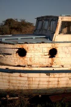 an old abandoned boat out of water with a blue sky.