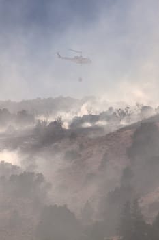 Fire fighting helicopter with smoke and the hillside. nevada