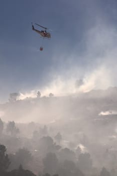 Fire fighting helicopter with smoke and the hillside. nevada