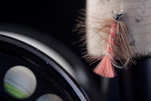 macro of a fly fishing reel and rod with a fly.