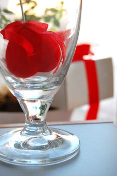 Gift box with red ribbon and fabric heart inside glass