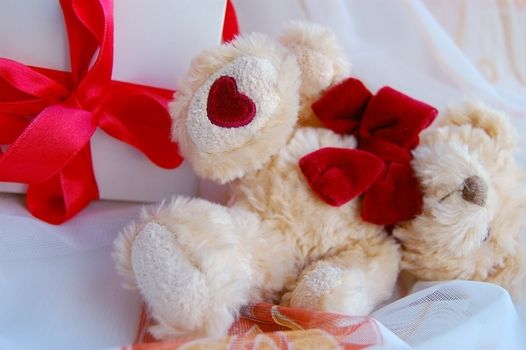 Gift box with red ribbon and teddy bear foot