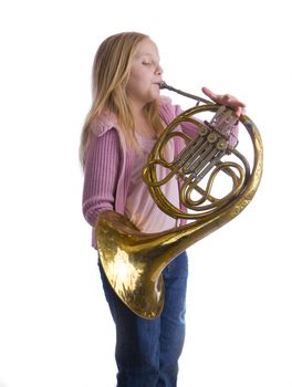 Girl playing an old French horn while standing