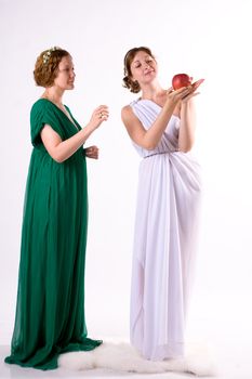 Two ladies in antique dress and one apple on white background
