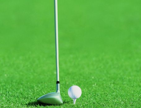 Golf ball behind driver at driving range