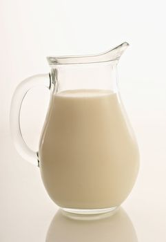 Glass jug with milk on a white background