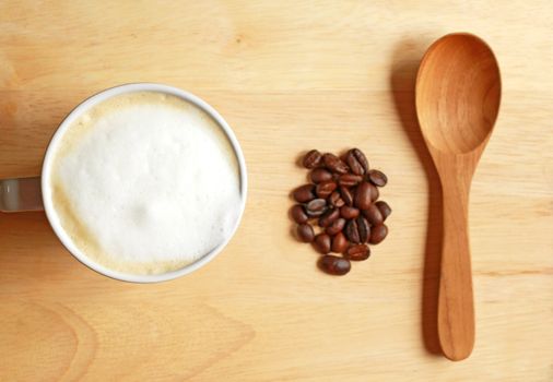 Latte coffee with bean and spoon on wooden table 