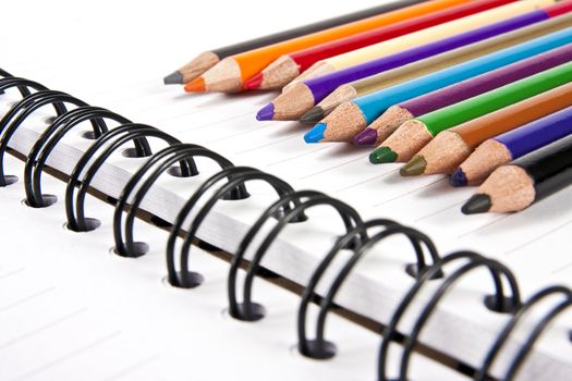 Color pencils in arrange in color wheel colors on note book